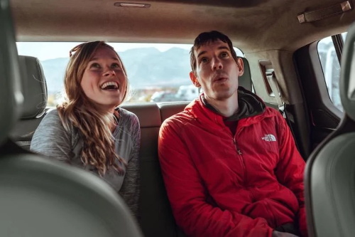 "Cheerful young man and woman sitting in the back seat of a car enjoying a road trip"
