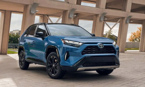 "Blue Toyota RAV4 compact SUV parked on a paved lot in front of a modern concrete building"