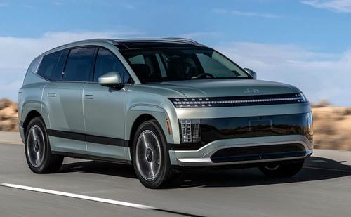 "Light green large new energy SUV driving on an open highway under a clear blue sky"