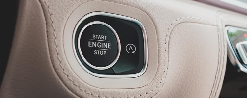"One-touch engine start button integrated with the automatic start-stop function symbol on the beige car interior panel"