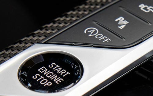"Car one-touch start button alongside the automatic start-stop OFF switch and parking assist button on the carbon fiber trim console"