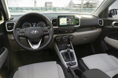 "Hyundai traditional fuel car interior, with dual mechanical pointer instruments, a small embedded central control screen, abundant physical buttons and an automatic gear lever"