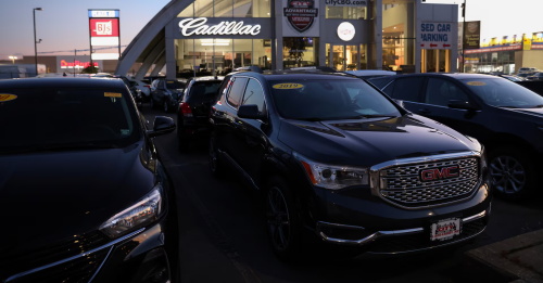 Outdoor parking lot of a Cadillac & GMC brand car dealership, with multiple brand new SUV models displayed for customer selection.