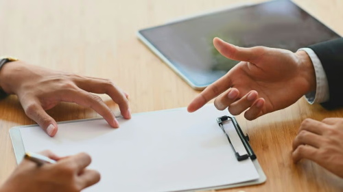 Negotiation scene between car buyers and sales staff. The salesperson explains the details of the car purchase contract on the clipboard before the customer signs it.