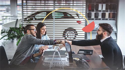 A customer shakes hands with an auto sales consultant after reaching a purchase agreement, marking the successful completion of the car deal.