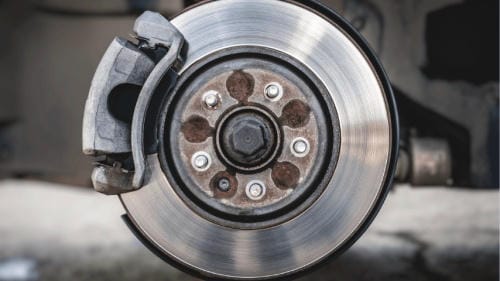"Close-up view of a car brake disc with brake caliper after removing the vehicle wheel"