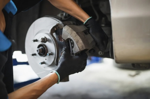 "Auto technician installing a brake caliper onto a new brake disc during vehicle brake maintenance"