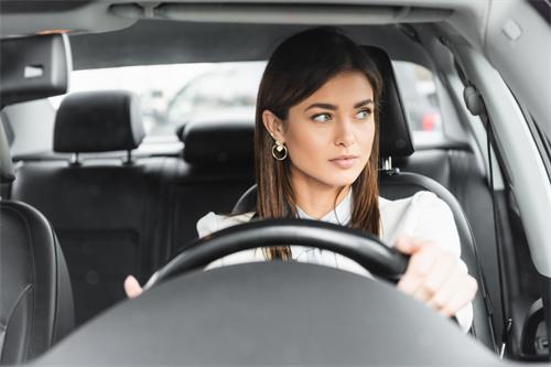 "Businesswoman focusing on driving while sitting in the driver's seat of a modern car"