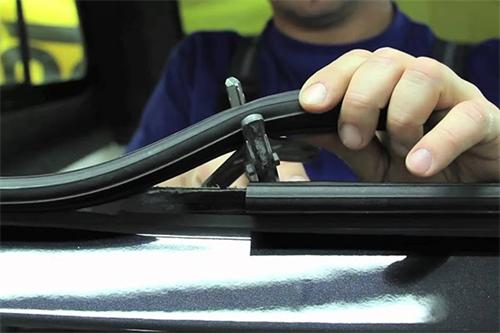 "Technician inspecting and repairing a damaged black rubber car door weather stripping seal"