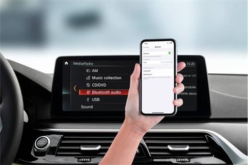 "Hand holding a smartphone pairing via Bluetooth with a car infotainment system showing Bluetooth audio option"