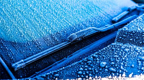 "Frost and ice covering a car windshield and frozen windshield wipers in cold winter weather"
