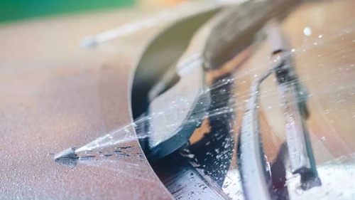 "Close-up shot of windshield washer fluid spraying onto a car front windshield from the vehicle nozzle"