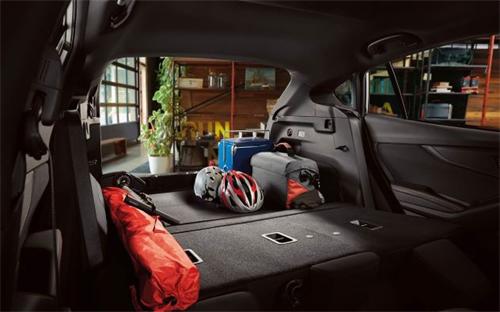 "Spacious car rear cargo area packed with travel luggage, bicycle helmets and outdoor gear"