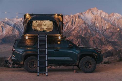 "Off-road SUV equipped with a rooftop tent parked in front of snow-capped mountains for wilderness camping"