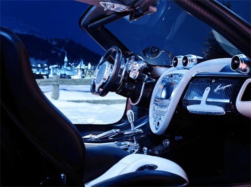 "Luxury black and white leather interior of a convertible sports car overlooking a snowy mountain village at night"